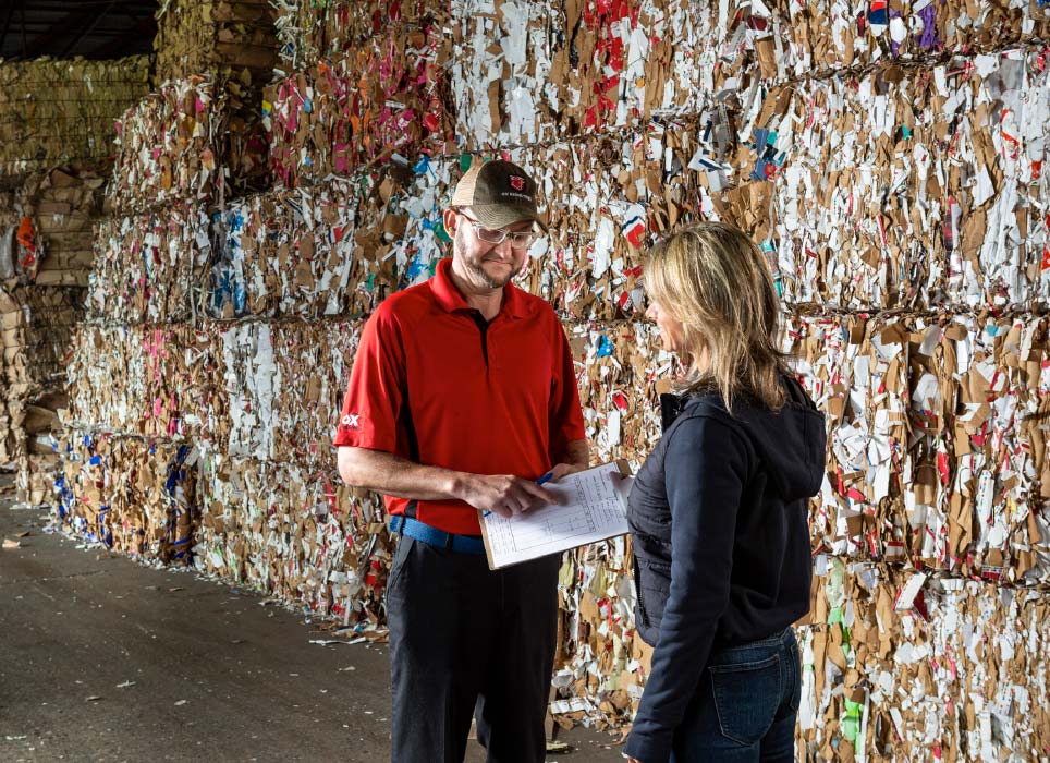 Man and woman near bales of recycled paper
